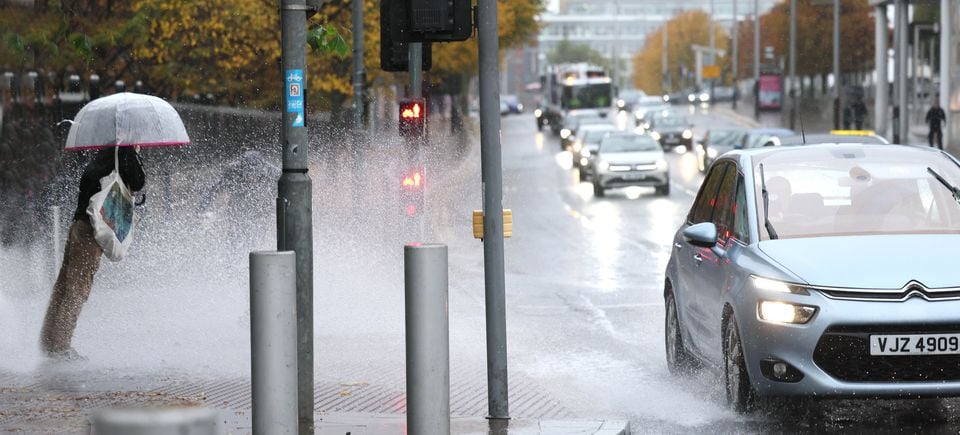 A pedestrian is soaked on Oxford Street, Belfast, on Friday as a car passes through a large puddle in the heavy rainfall of Storm Amy. Stephen Davison.